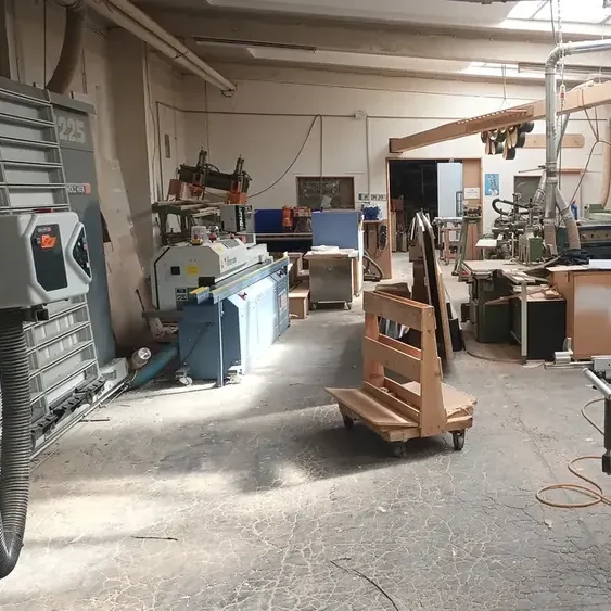 Werkstatt mit Holzbearbeitungsmaschinen und Werkzeugen und Holzwagen.