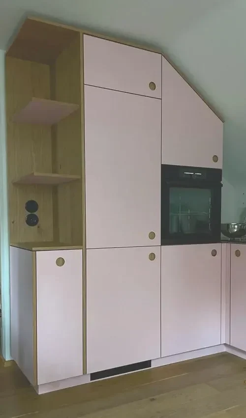 Moderne Einbauküche in einer Dachschräge mit rosa Fronten und Eiche. Passgenaue Arbeit von einem Schreiner