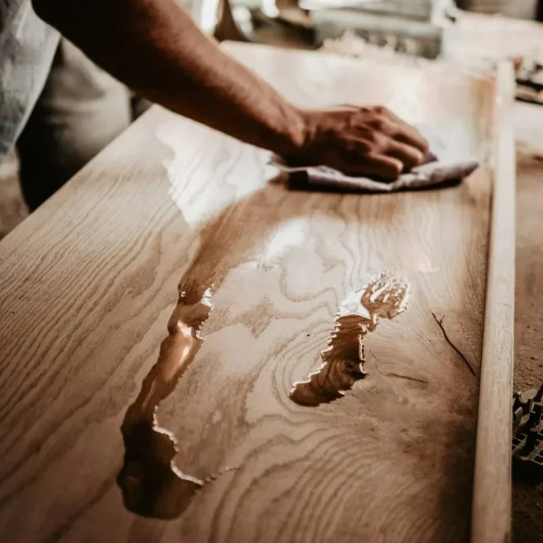Ein Handwerker wischt Holzöl von einer behandelten Holzoberfläche ab.